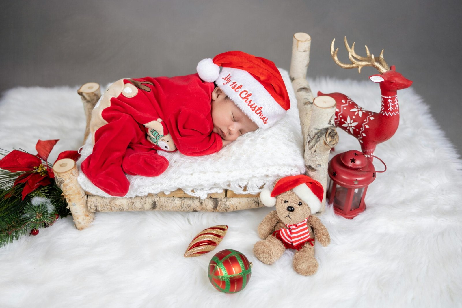 Newborn baby sleeping with decorations in a Christmas-themed studio shoot in India.