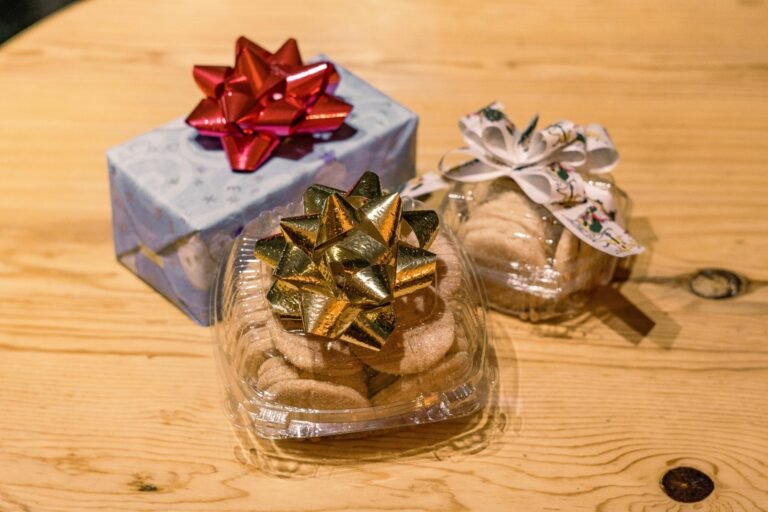 Decorative gift box and cookies wrapped with festive bows on a wooden table, ideal for holiday themes.