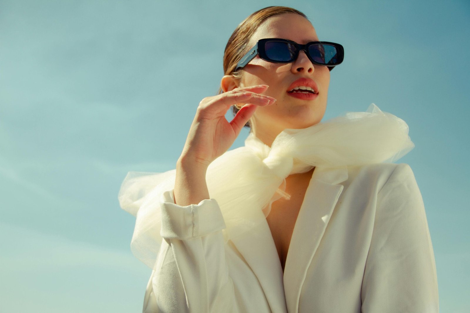 Low angle of stylish female model in sunglasses standing with opened mouth and looking away