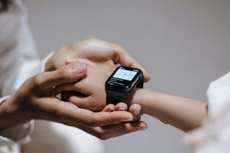 Close-up of an adult helping a child with a smartwatch, showcasing modern technology and parental guidance.